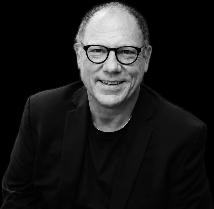 Tim Miner, founder and CEO of By The People Technologies, in black and white, smiling, in round dark glasses and a dark jacket.
